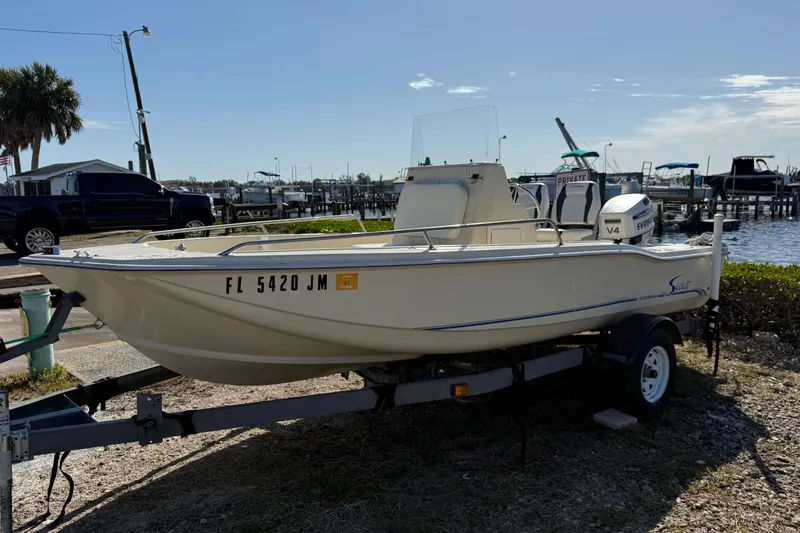 Slide: The Image of 1995 Scout 172 Sportfish boat on trailer near waterfront, sunny day. - 2