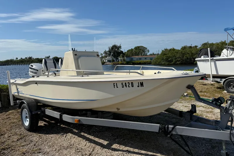 Slide: The Image of 1995 Scout 172 Sportfish boat on trailer by waterfront, under clear blue sky. - 3