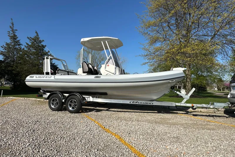 Slide: The Image of 2024 Highfield Sport 660 boat on trailer, parked outdoors under clear blue sky. - 12