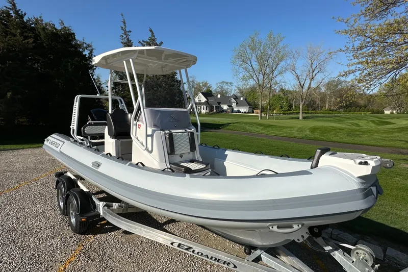 Slide: The Image of 2024 Highfield Sport 660 boat on trailer, parked outdoors near a grassy area. - 13