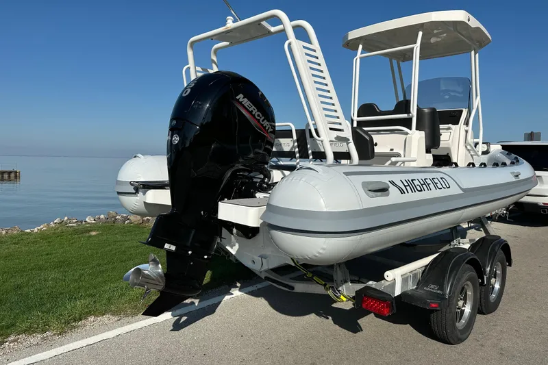Slide: The Image of 2024 Highfield Sport 660 boat on trailer by the water, featuring a Mercury outboard engine. - 4