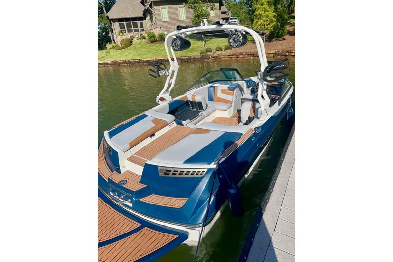 Slide: The Image of 2020 Nautique Super Air Nautique 210 boat docked on a serene lake. - 3