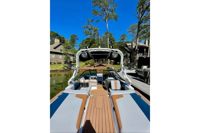 Slide: The Image of 2020 Nautique Super Air Nautique 210 boat docked by a lakeside house. - 4