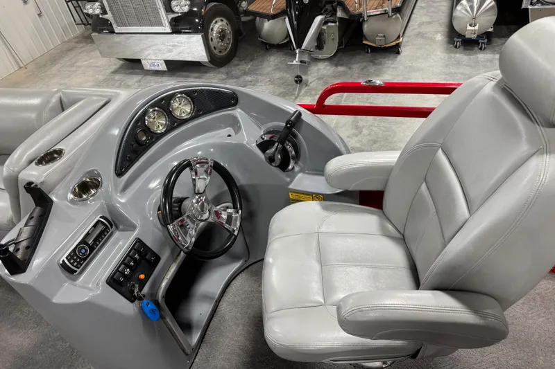 Slide: The Image of 2014 Bentley Pontoons 243 Cruise helm with steering wheel and captain's chair in a showroom. - 10