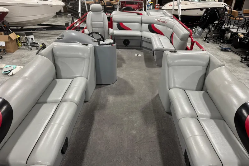 Slide: The Image of 2014 Bentley Pontoons 243 Cruise interior with gray seating and red accents in a showroom. - 7