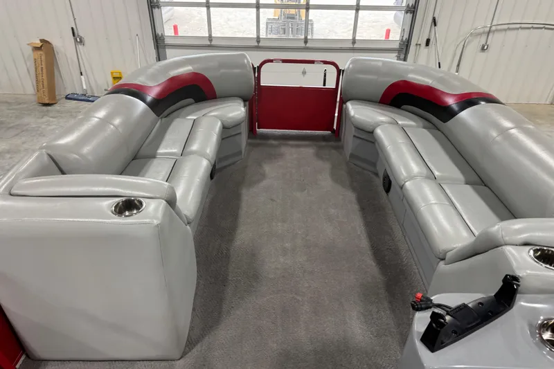 Slide: The Image of 2014 Bentley Pontoons 243 Cruise interior with gray and red seating in a garage setting. - 9