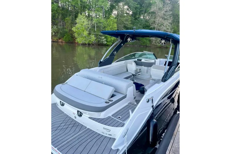 Slide: The Image of 2022 Sea Ray SLX 280 boat with luxurious seating, docked by a serene lake. - 2