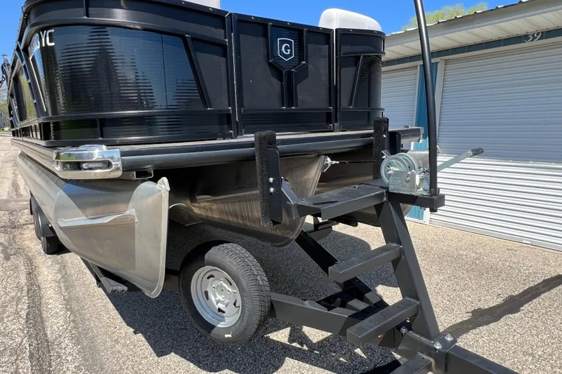 Slide: The Image of 2023 Godfrey Monaco 235 SB pontoon boat on trailer, parked near storage unit. - 11