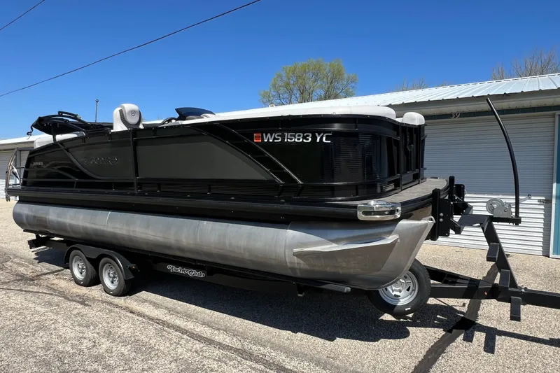 Slide: The Image of 2023 Godfrey Monaco 235 SB pontoon boat on trailer, parked outdoors. - 2