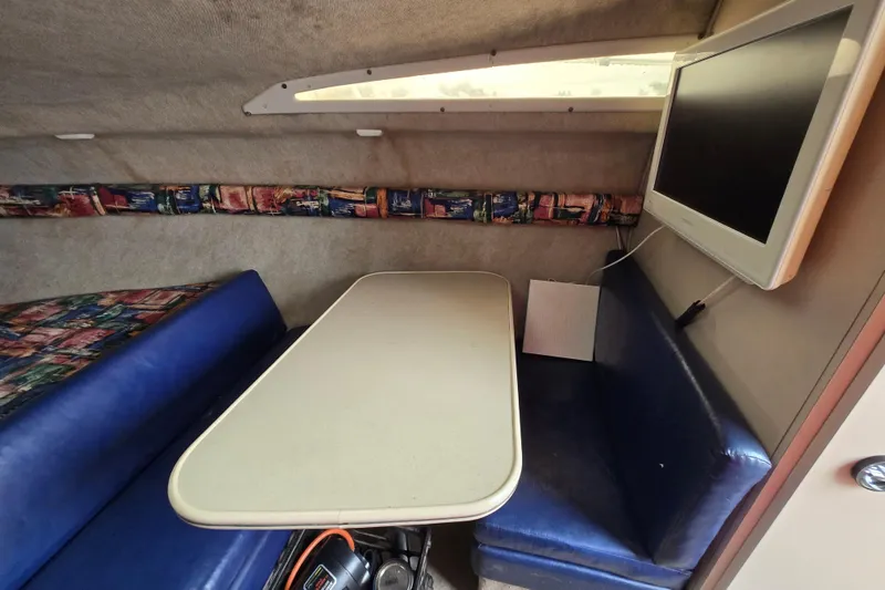 Slide: The Image of Interior of a 1996 Wellcraft 26 Exel SE boat with table, seating, and mounted TV. - 19