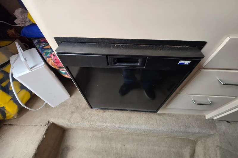 Slide: The Image of Interior of 1996 Wellcraft 26 Exel SE boat featuring a compact black refrigerator. - 24