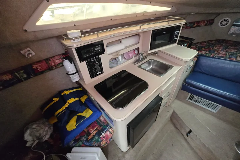 Slide: The Image of Interior of a 1996 Wellcraft 26 Exel SE boat featuring a compact kitchen area. - 26