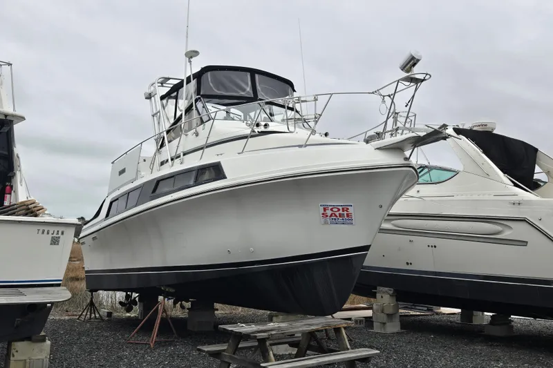 Slide: The Image of 1987 Carver 32 Mariner boat for sale, displayed on stands, with adjacent vessels. - 14