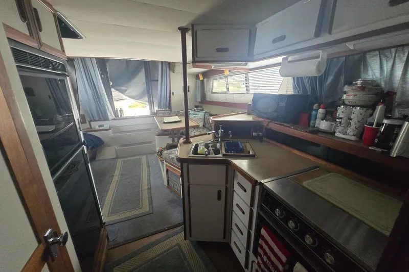 Slide: The Image of Interior of a 1987 Carver 32 Mariner boat, featuring a compact kitchen and dining area. - 18