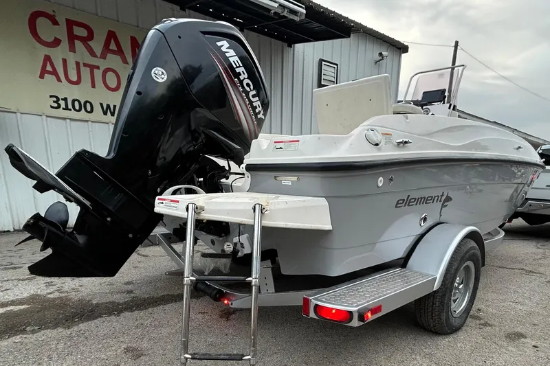 Slide: The Image of 2019 Bayliner Element F18 boat on trailer, parked outdoors under a clear sky. - 2