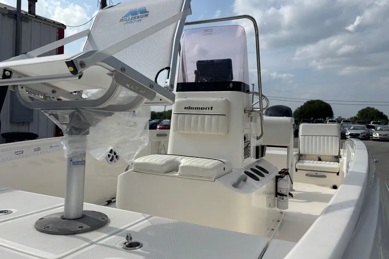 Slide: The Image of 2019 Bayliner Element F18 boat interior with seating and console, under a partly cloudy sky. - 47