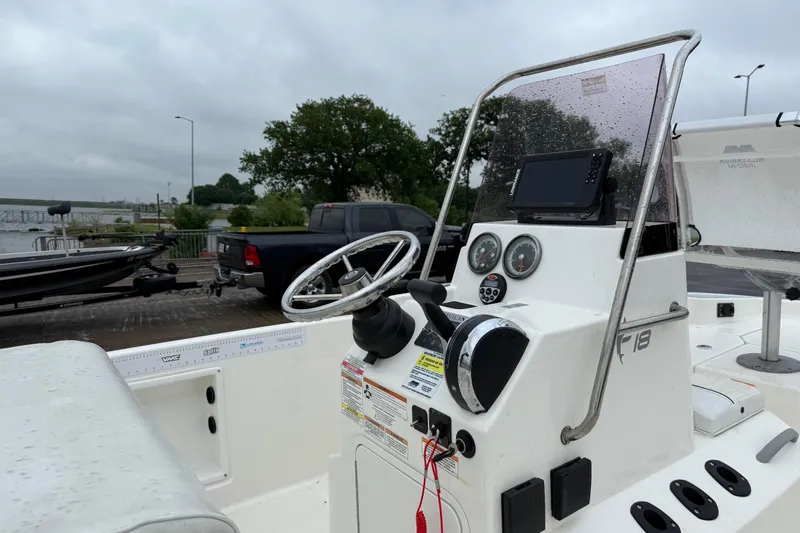 Slide: The Image of 2019 Bayliner Element F18 boat dashboard with steering wheel and controls, parked near a dock. - 70