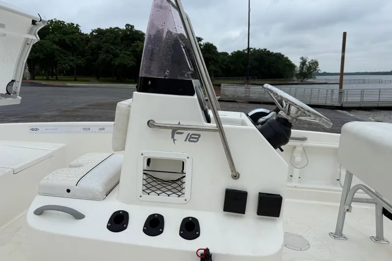 Slide: The Image of 2019 Bayliner Element F18 boat console with steering wheel and controls, docked by a lake. - 73