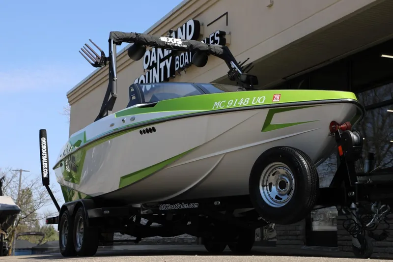 Slide: The Image of 2019 Axis T22 boat with green accents on a trailer outside a dealership. - 13