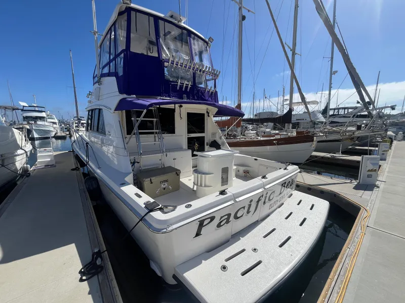Slide: The Image of Eine Riviera 43 Open Flybridge von 1997 liegt im Hafen. Sie hat ein blaues Verdeck und eine geräumige Plattform. - 2