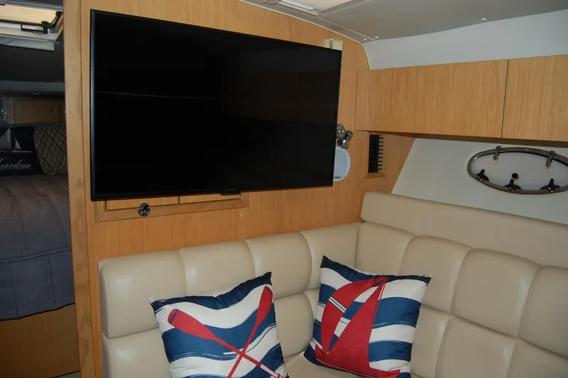 Slide: The Image of Interior of 2004 Tiara Yachts 3500 Open with TV, beige seating, and nautical pillows. - 11