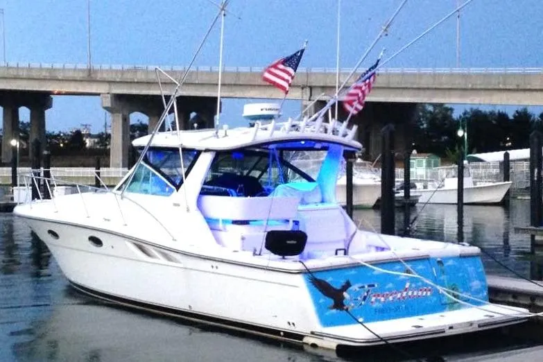 Slide: The Image of 2004 Tiara Yachts 3500 Open docked, featuring American flags and blue accent lighting. - 2