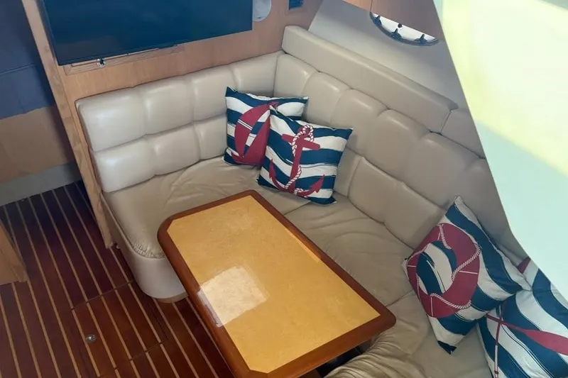 Slide: The Image of Interior of 2004 Tiara Yachts 3500 Open with nautical-themed cushions and wooden table. - 9