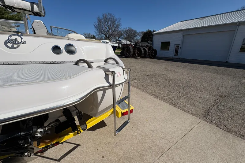 Slide: The Image of 2005 Tahoe Q4 SF boat with ladder, parked near a building under clear skies. - 27