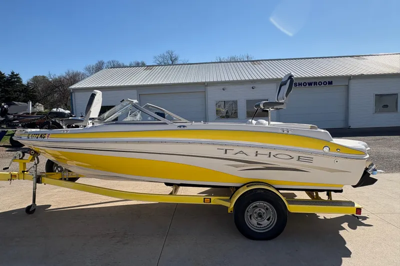 Slide: The Image of 2005 Tahoe Q4 SF boat in yellow and white on trailer, parked outside showroom. - 4