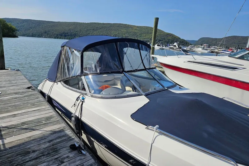 Slide: The Image of 2013 Stingray 234 LR boat docked by a scenic lake with hills in the background. - 2