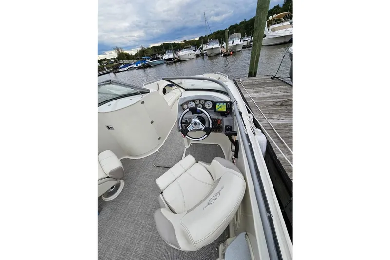 Slide: The Image of 2013 Stingray 234 LR boat interior at dock, featuring steering wheel and dashboard controls. - 5