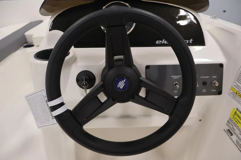 Slide: The Image of Steering wheel of 2026 Bayliner Element E16 boat, featuring control panel and ignition key. - 26