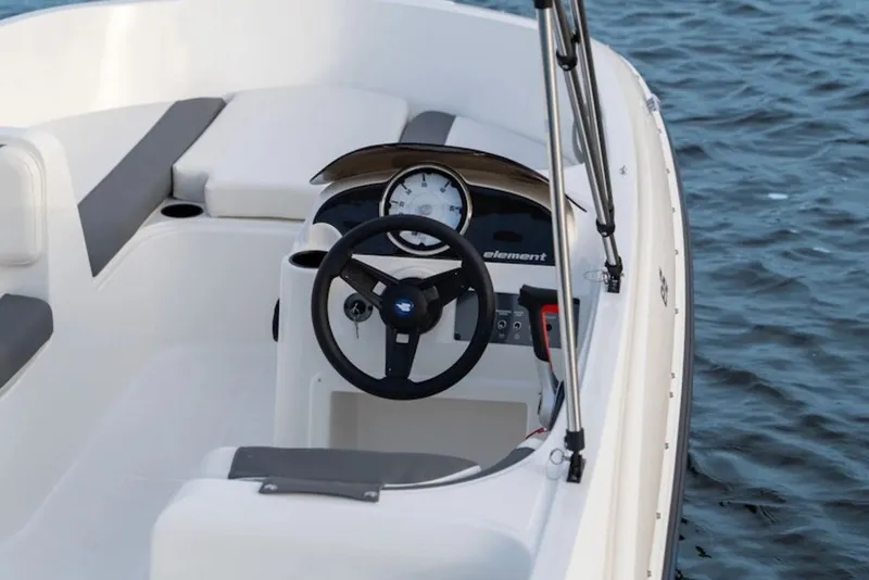 Slide: The Image of 2026 Bayliner Element E16 boat interior with steering wheel, on calm water. - 41