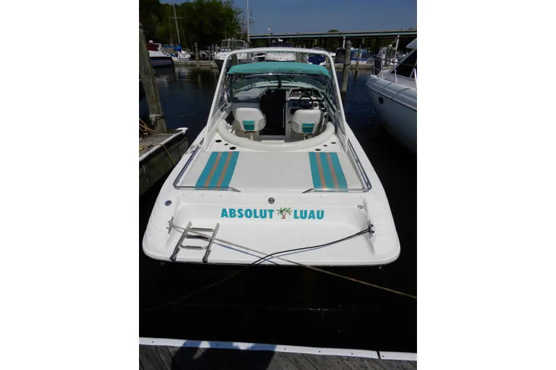 Slide: The Image of 1994 Sea Ray 310 Sun Sport boat docked, featuring "Absolut Luau" text on the stern. - 2