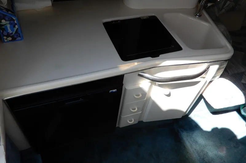 Slide: The Image of 1994 Sea Ray 310 Sun Sport interior kitchenette with sink and storage. - 21