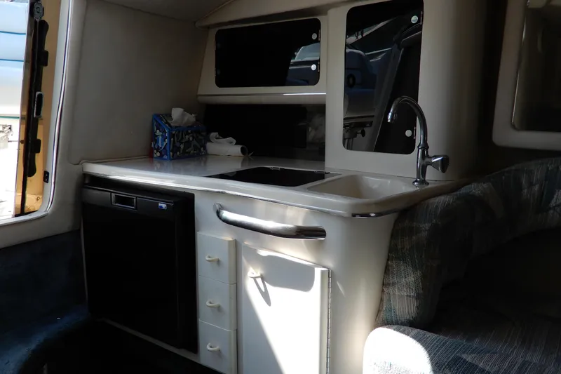 Slide: The Image of Interior of 1994 Sea Ray 310 Sun Sport boat featuring kitchenette with sink and storage. - 26