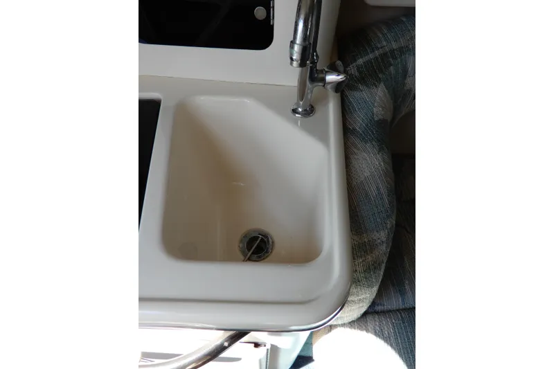 Slide: The Image of 1994 Sea Ray 310 Sun Sport boat sink with chrome faucet and cushioned seating. - 29