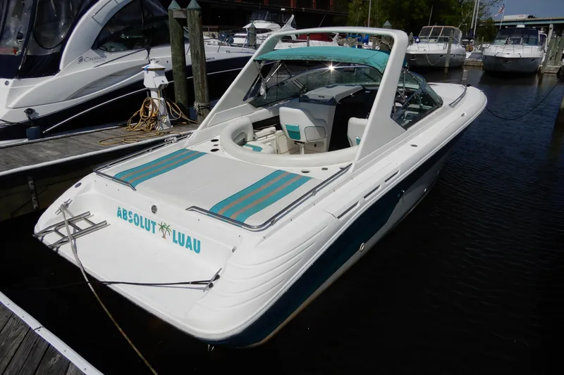 Slide: The Image of 1994 Sea Ray 310 Sun Sport boat docked, featuring "Absolut Luau" on the stern. - 4