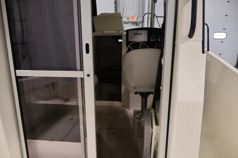 Slide: The Image of 2026 Bayliner Trophy T23 Pilothouse interior with helm and seating area. - 18