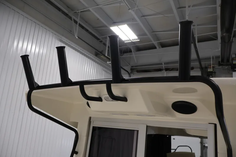 Slide: The Image of 2026 Bayliner Trophy T23 Pilothouse roof with rod holders in a garage setting. - 54