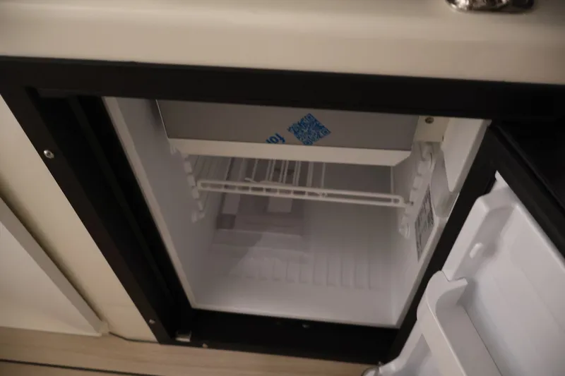 Slide: The Image of Open refrigerator inside 2026 Bayliner Trophy T23 Pilothouse boat, showcasing interior storage space. - 34