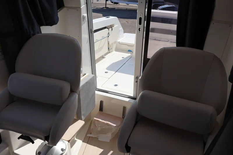 Slide: The Image of Interior of 2026 Bayliner Trophy T23 Pilothouse with two cushioned seats and open door. - 68