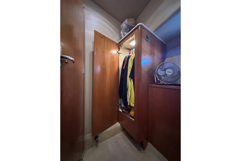 Slide: The Image of Wooden closet interior on a 2003 Meridian 381 Sedan yacht, with clothes and a fan. - 13
