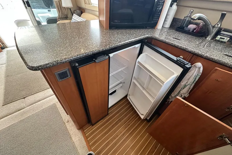 Slide: The Image of 2003 Meridian 381 Sedan yacht interior with open mini fridge and granite countertop. - 26