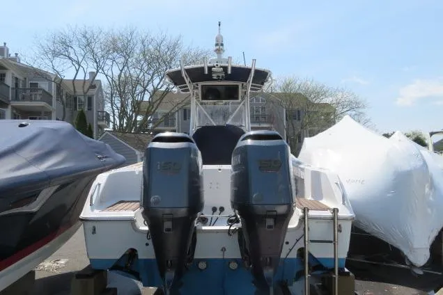 The Image of 2006 Sea Hunt Triton 260 boat with dual outboard motors, docked near residential buildings. - 0