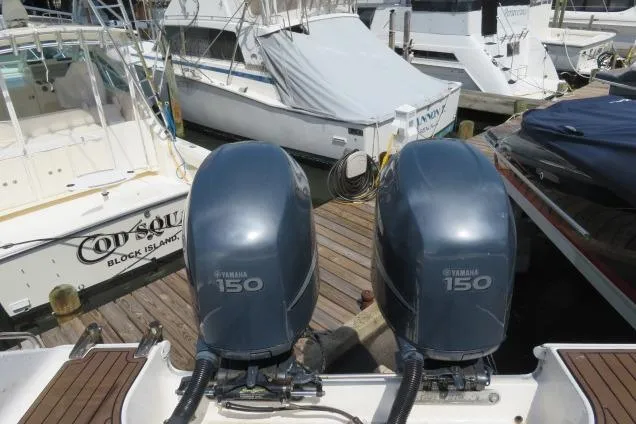 Slide: The Image of Twin Yamaha 150 engines on a 2006 Sea Hunt Triton 260 at a marina. - 2