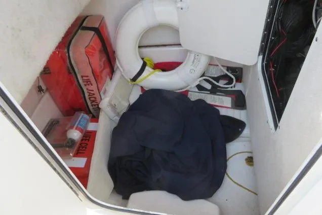 Slide: The Image of Storage compartment of 2006 Sea Hunt Triton 260 with life jackets and safety equipment. - 26