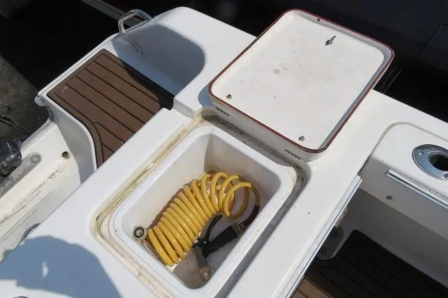 Slide: The Image of 2006 Sea Hunt Triton 260 boat deck with storage compartment and coiled hose. - 6