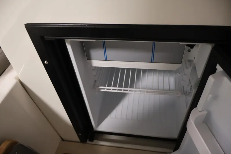 Slide: The Image of Open refrigerator inside 2026 Bayliner Trophy T25 Pilothouse boat, showcasing interior storage space. - 56