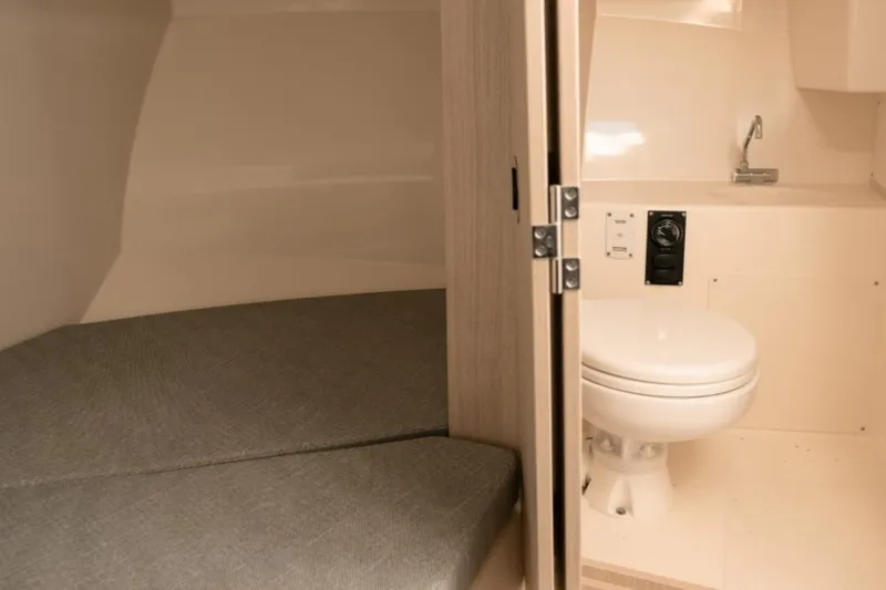 Slide: The Image of 2026 Bayliner Trophy T25 Pilothouse interior with bed and compact bathroom. - 3
